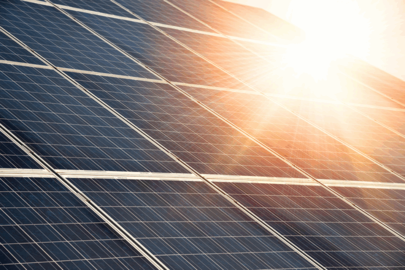 Es sind Solarpanele zu sehen. Die Sonne scheint im rechten oberen Eck des Bildes darauf.