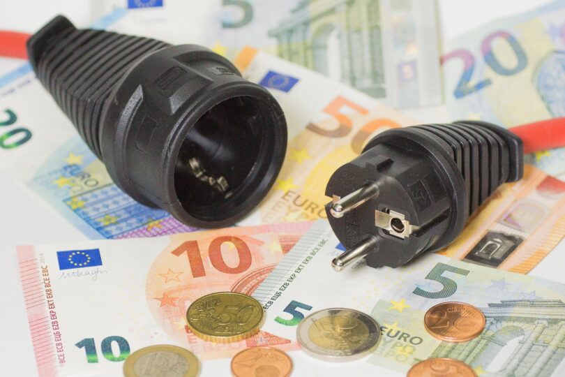 Fotos eines nicht eingesteckten Steckers und einer Steckdose, die auf Bargeld liegen.