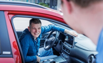 Mitfahrbörse, eine Person hinter dem Lenkrad, eine einsteigende Person