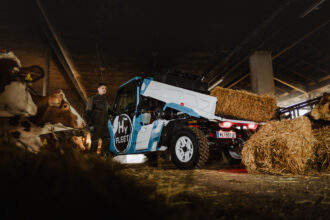 Ein blaues Nutzfahrzeug steht neben Heuballen in einer Scheune