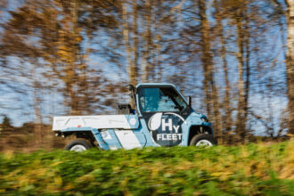 Ein fahrendes blaues Nutzfahrzeug von der Seite mit dem Schriftzug HyFleet.