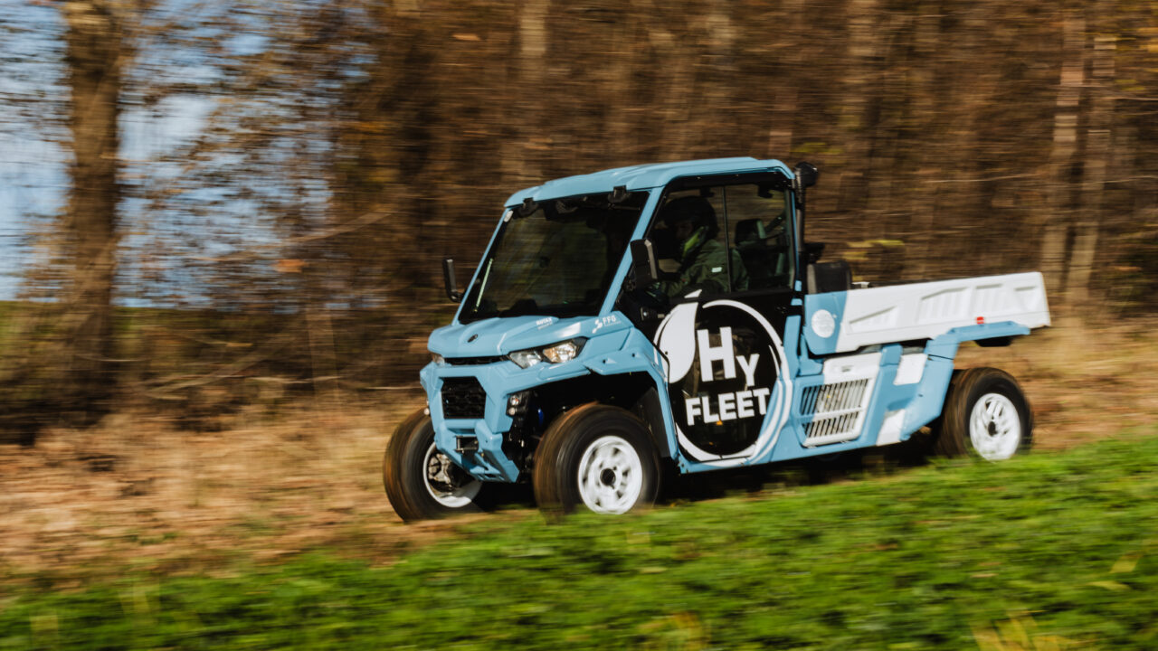 Ein fahrendes blaues Nutzfahrzeug von der Seite mit dem Schriftzug HyFleet.