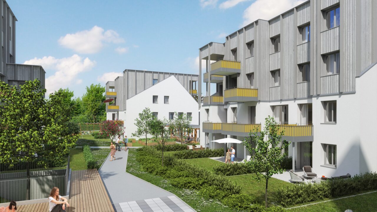 Wohnhausanlage Friedrich-Inhauser-Straße. Moderne Wohnanlage mit mehrstöckigen Gebäuden, die eine grüne Gemeinschaftsfläche umgeben. Balkone mit gelben Akzenten, breite Gehwege und bepflanzte Gärten schaffen eine einladende Atmosphäre. Menschen genießen die Außenbereiche, während Kinder spielen und Fahrrad fahren – eine Szene urbanen Wohnens mit nachhaltigem Flair.