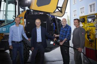 Personen vor ladendem Radlader (Wasserstoff)