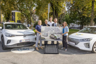 Personen mit Plakat neben E-Taxis und Matrix Ladestation.