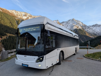 Foto eines fahrenden weißen FCE-Busses vor bergiger Landschaft.
