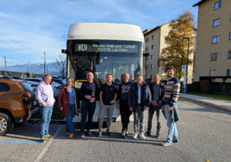 Neun Menschen stehen vor einem weißen FCE-Bus.