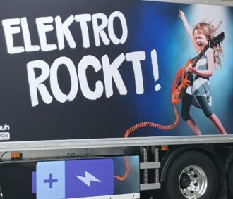 Werbung auf der LKW-Seite, die eine Gitarre spielende Person mit dem Text „ELEKTRO ROCKT!“ zeigt.