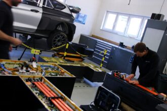Eine Person, die in einer Autowerkstatt arbeitet, mit ausgebreiteten Autoteilen und Werkzeugen.