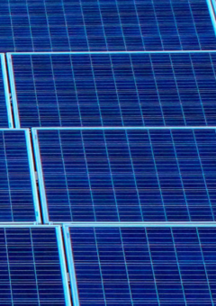 Detailansicht mehrerer Solarmodule, die in einem Raster angeordnet sind. Die dunkelblauen Panels mit feinen Linien reflektieren leicht das Licht und symbolisieren erneuerbare Energiequellen.