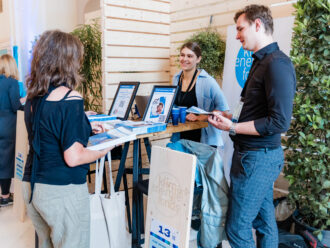 Vier Personen stehen an einem Messestand des 