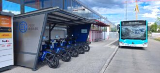 Eine Sharing Station für einspurige elektrische Fahrzeuge neben einer Bushaltestation.