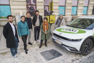 Personen stehen vor einem Auto mit Aufschrift 