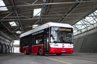 Rot-weißer öffentlicher mit Wasserstoff betriebener Bus in einer Halle.