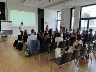 Publikum bei einer Präsentation in einem modernen Konferenzraum mit Projektorbildschirm.