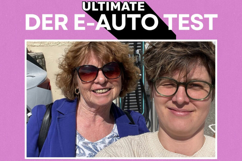 Zwei Frauen, eine ältere mit Sonnenbrille und eine jüngere mit Brille, vor einem Elektroauto an einer Ladestation, Text 'Ultimate Der E-Auto Test', Interview mit Marcella Kral
