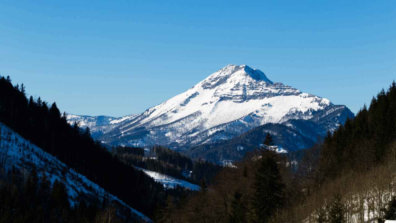 Aussicht auf den Ötscher vom Annaberg im Winter. Der Berg ist schneebedeckt und der Himmel ist blau.