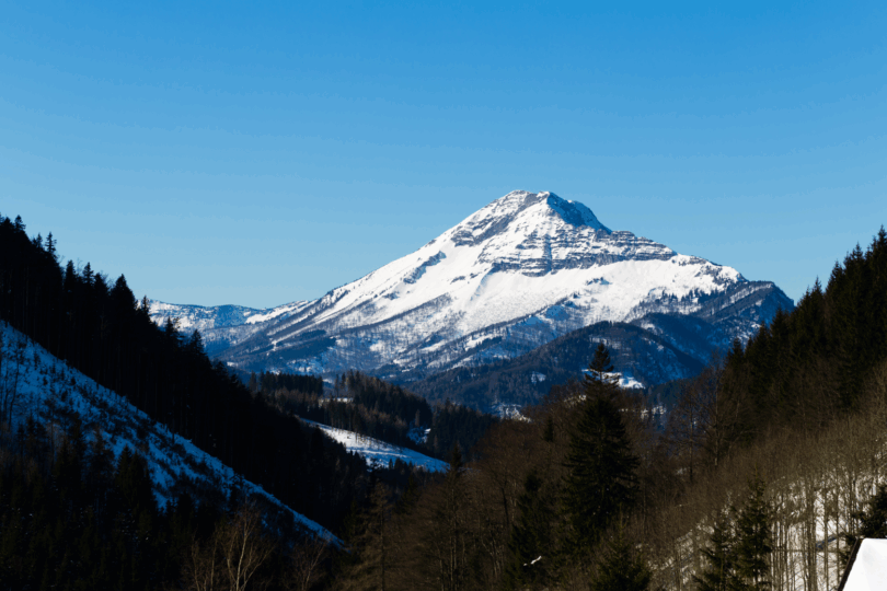 Aussicht auf den Ötscher vom Annaberg im Winter. Der Berg ist schneebedeckt und der Himmel ist blau.
