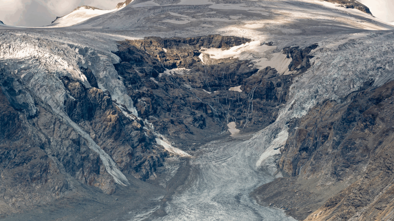 Berg mit Gletscherzunge vor blauem, bewölktem Himmel.
