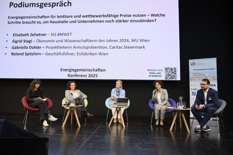 Alle Podiumsdiskutanten und die Moderatorin auf der Bühne sitzend bei der Energiegemeinschaften Konferenz 2025