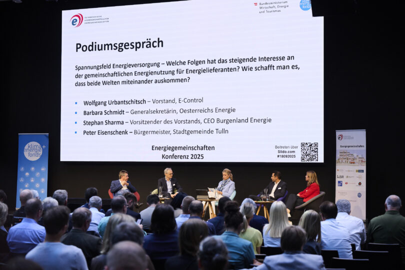Alle Podiumsdiskutanten und die Moderatorin auf der Bühne sitzend bei der Energiegemeinschaften Konferenz 2025