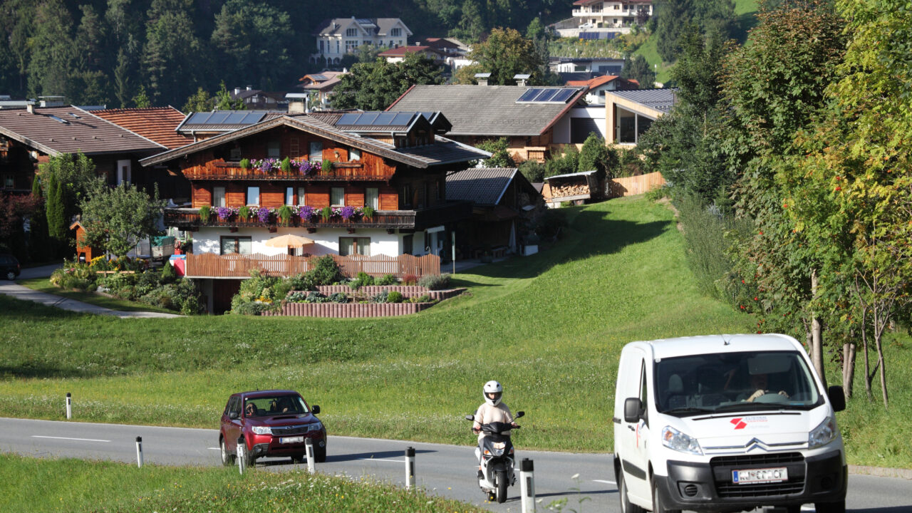 Zwei Autos und ein Motorrad auf der Straße im wunderschönen Tirol.