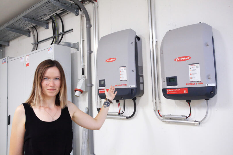 Junge Frau vor Solarwechselrichter