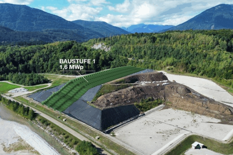 Luftaufnahme einer Baustelle in bergiger Landschaft mit grün markiertem Bereich und Text 'BAUSTUFE 1 1,6 MWp'.