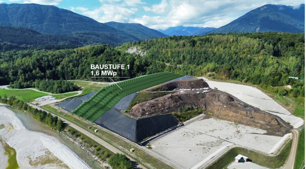 Luftaufnahme einer Baustelle in bergiger Landschaft mit grün markiertem Bereich und Text 'BAUSTUFE 1 1,6 MWp'.