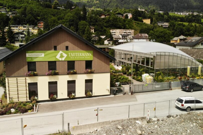 Firmengebäude im Vordergrund und rechts daneben ein Gewächshaus