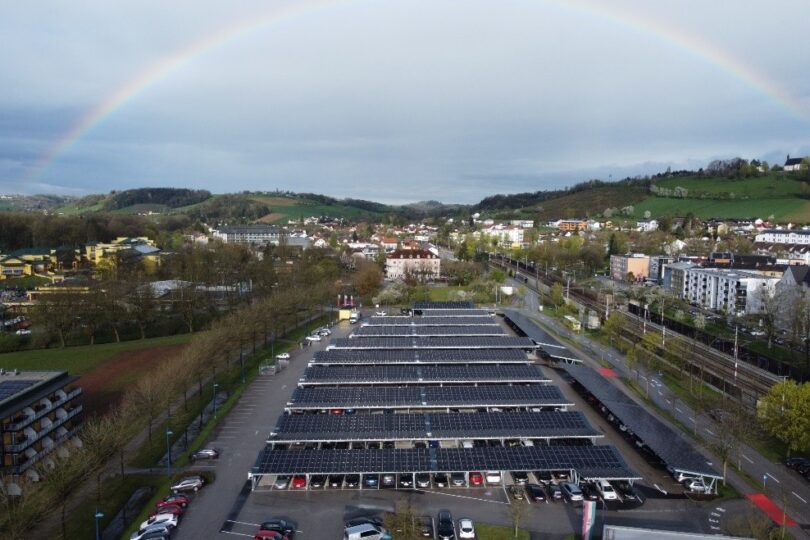 Parkplatz mit PV-Überdachung in Landschaft mit Regenbogen
