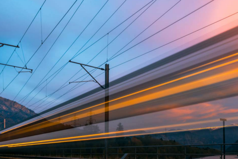 Landschaft mit Bergen und Stromleitungen vor einem Himmel mit Wolken und Lichtstreifen, die Bewegung andeuten