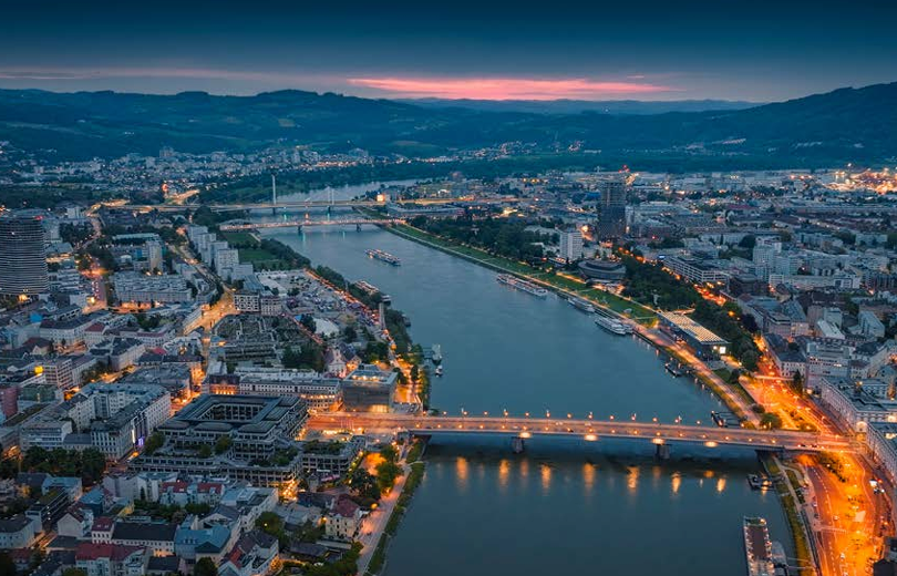 Eine Stadt bei Nacht, durch die ein Fluss fliest, aus der Vogelperspektive.