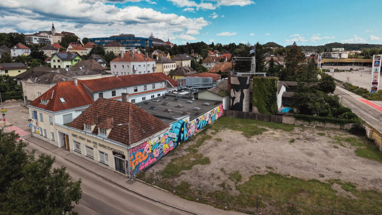 Luftaufnahme der Tischlerei Melk mit historischen Gebäuden, bunten Graffiti an den Fassaden und Blick über die umliegende Stadtlandschaft von Melk