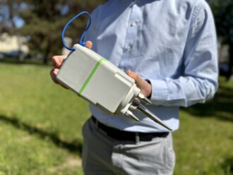Foto: Ein Seismometer, gehalten von einem Mann.